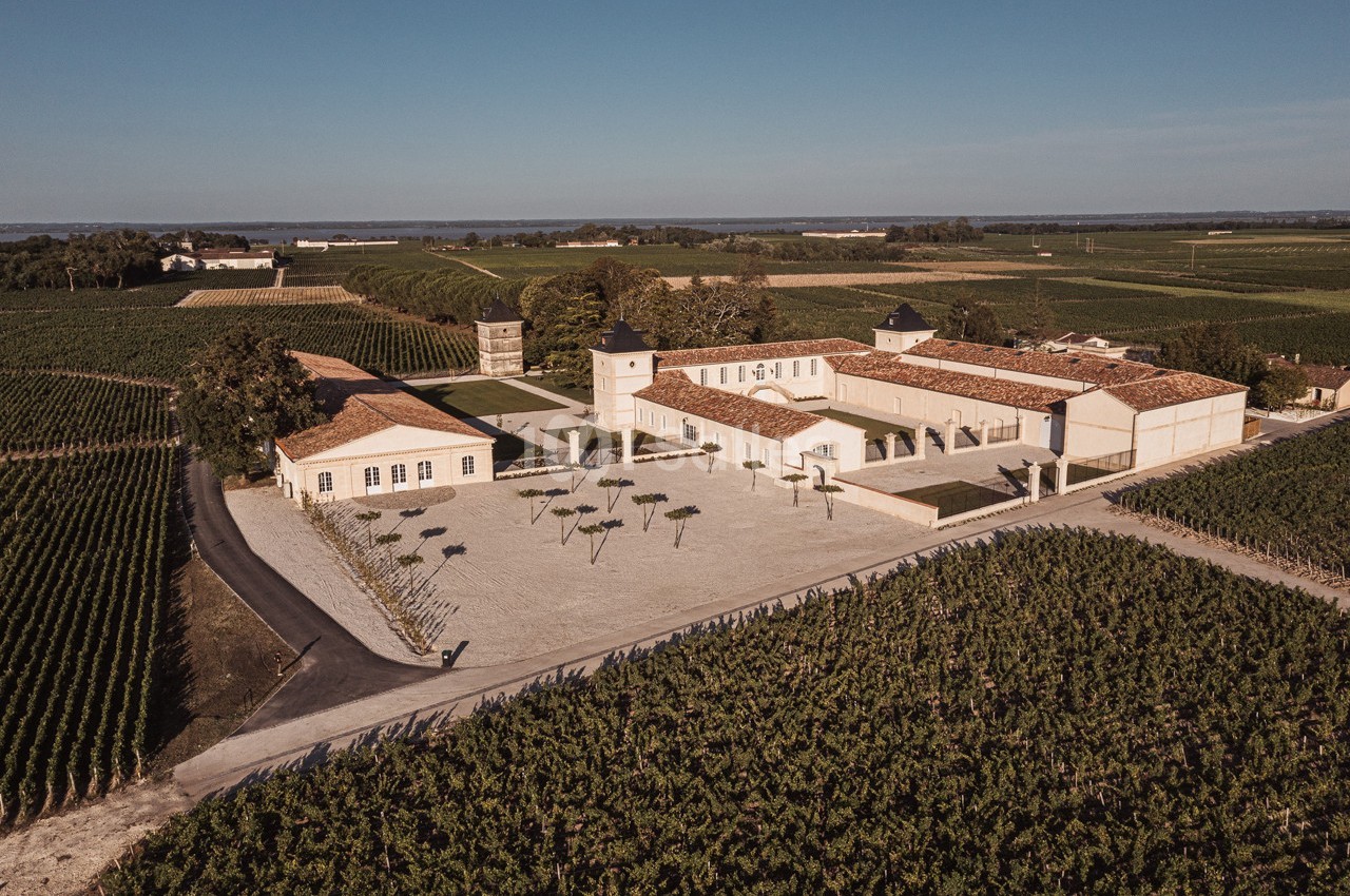 Vue aérienne d'un domaine viticole avec bâtiments en pierre, cour centrale et vignobles environnants.