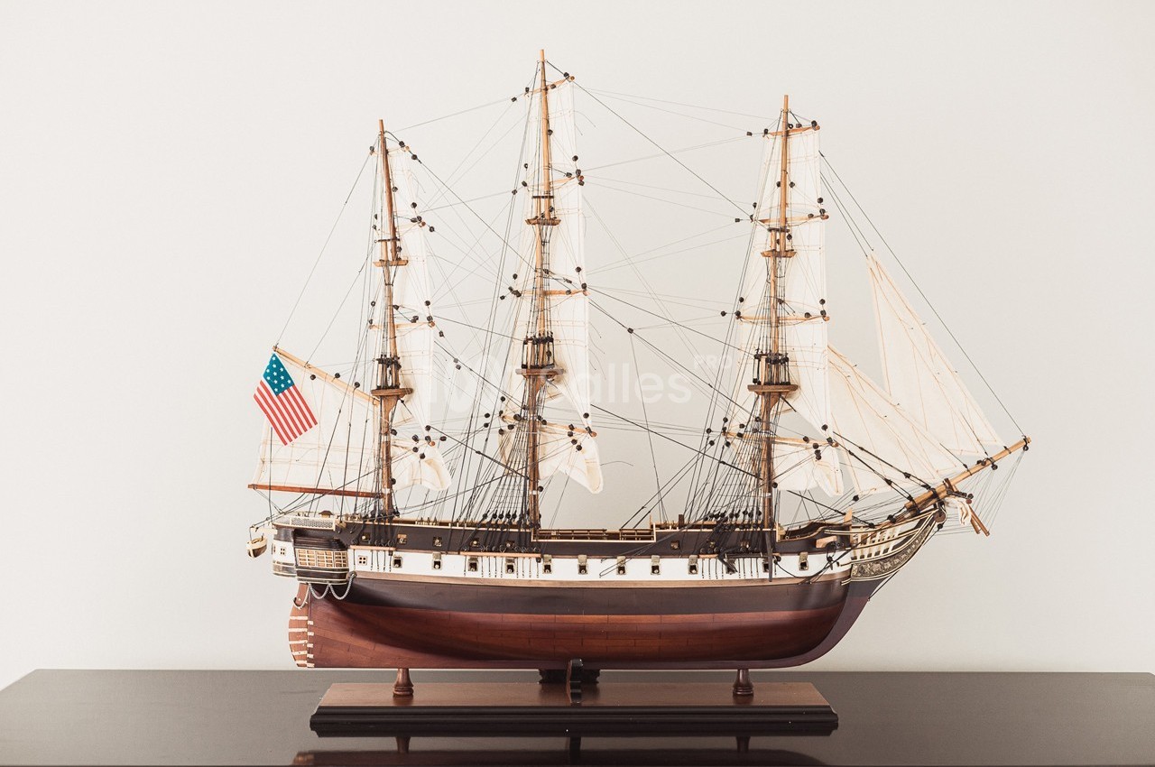 Maquette détaillée d'un voilier ancien avec trois mâts, posée sur une surface sombre, drapeau américain visible.