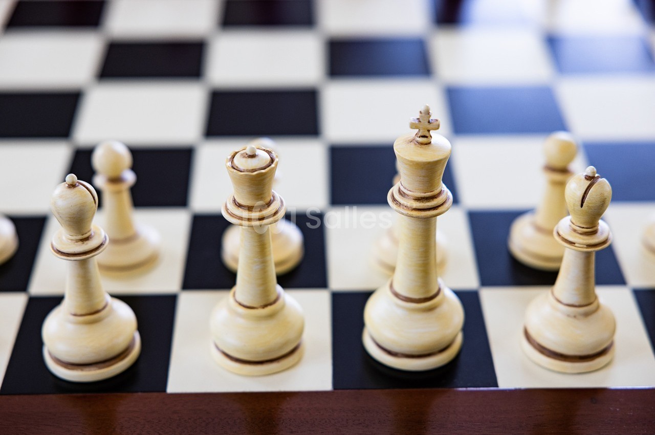 Pièces d'échecs en bois disposées sur un échiquier noir et blanc.