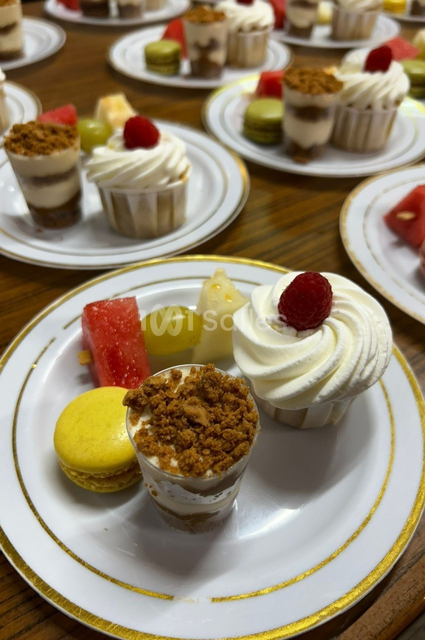 Assortiment de desserts sur une assiette, incluant verrines, macaron, fruits frais et pâtisseries.