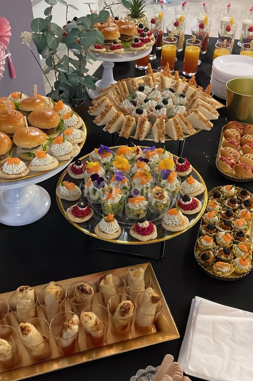Buffet de pièces cocktail variées comprenant sandwichs, verrines, mini-burgers, feuilletés et jus de fruits.