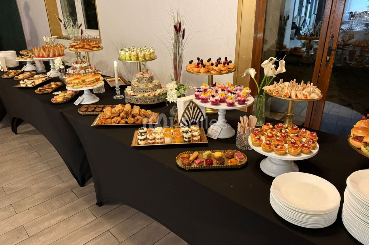 Buffet de desserts et amuse-bouches variés disposés sur des tables noires avec une présentation soignée.
