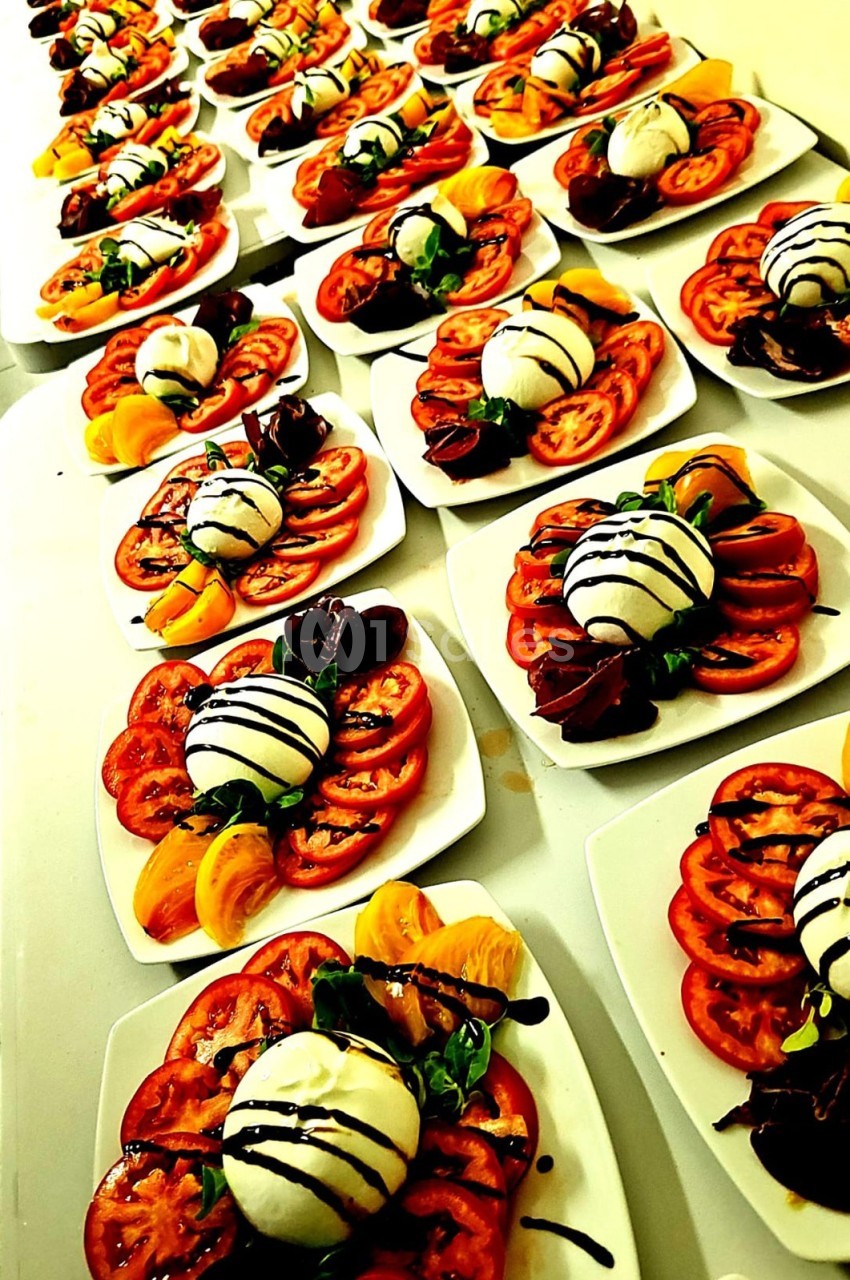 Assiettes de salade caprese alignées, composées de tomates, mozzarella, basilic et filet de vinaigre balsamique.