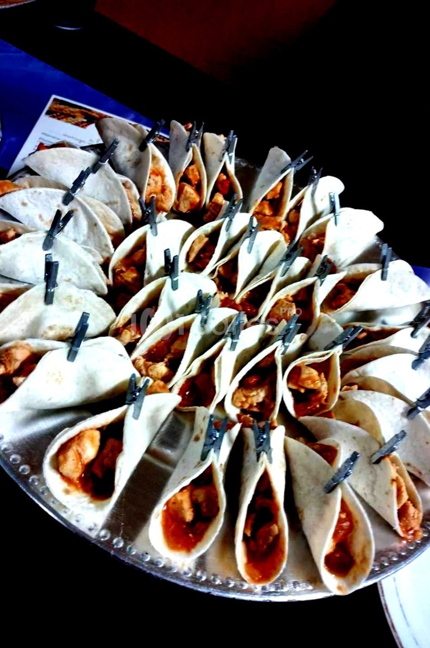 Plateau de mini-tacos garnis de poulet et maintenus par des pinces, disposés en cercle sur un plat.