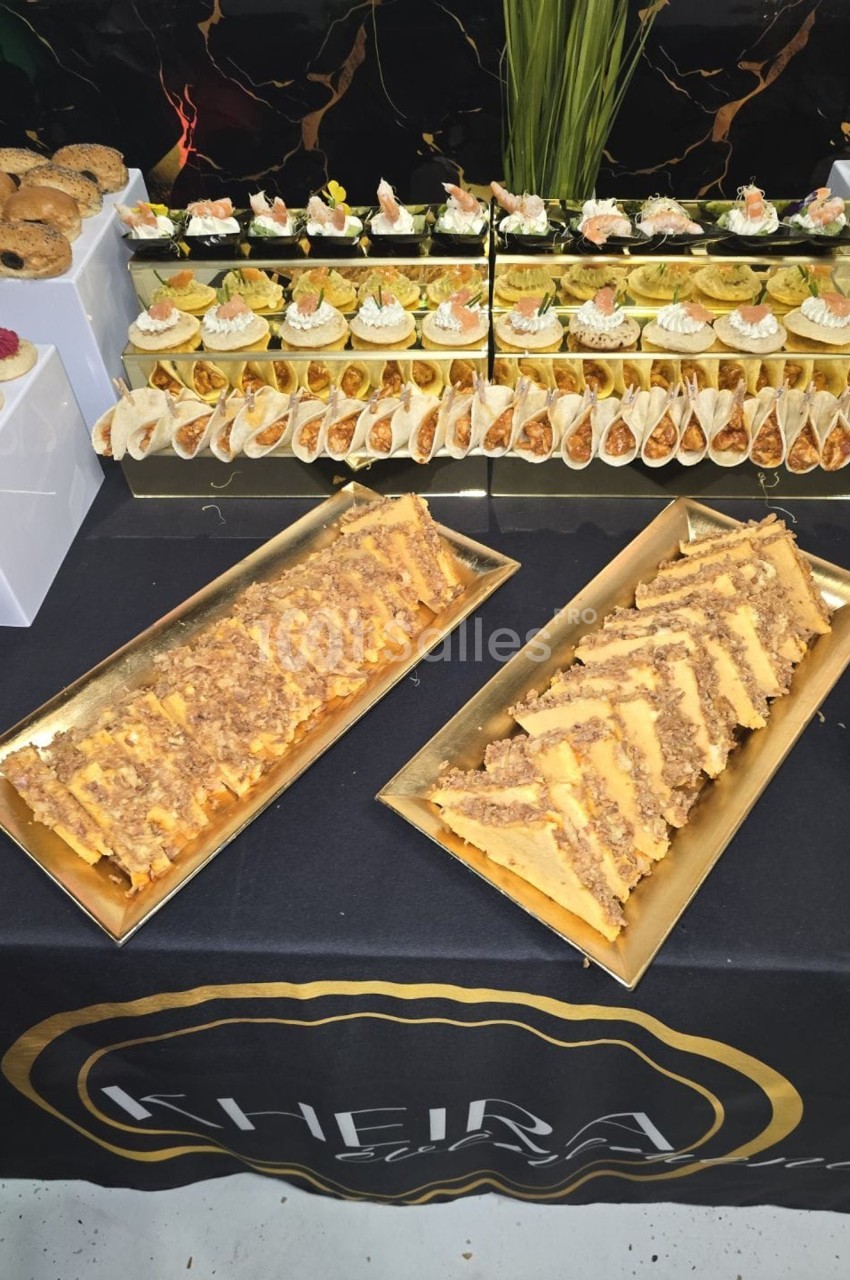 Plateau de pâtisseries variées et de desserts salés présentés sur une table décorée avec une nappe noire.
