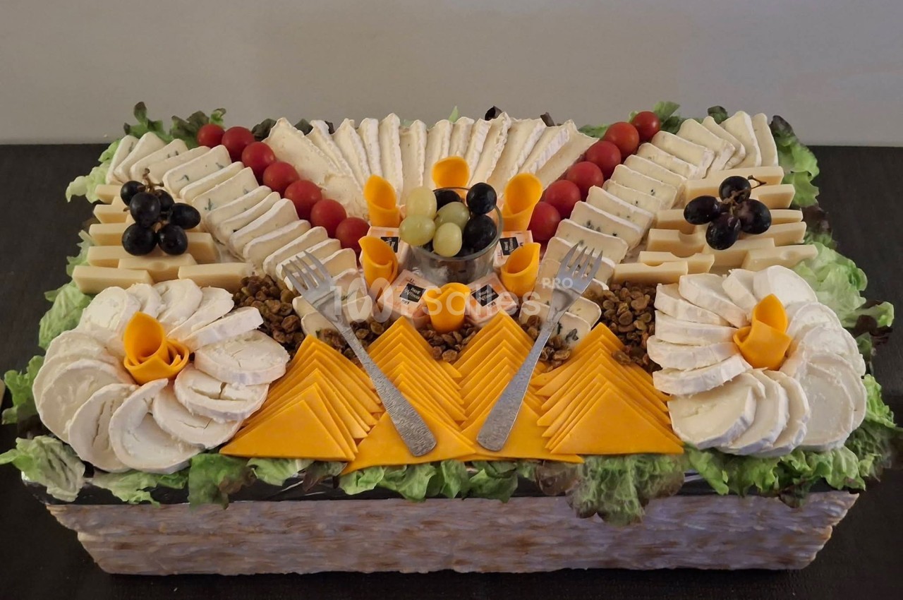 Plateau de fromages variés joliment disposés avec raisins, tomates cerises et décorations sur un lit de salade.