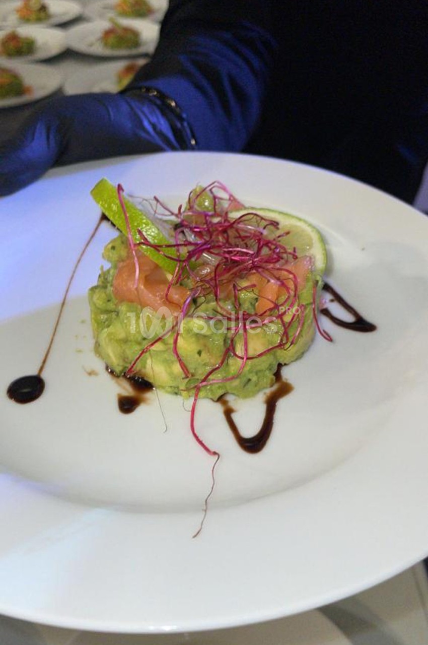 Entrée composée d'avocat, saumon fumé, germes rouges et rondelle de citron, décorée de sauce balsamique.