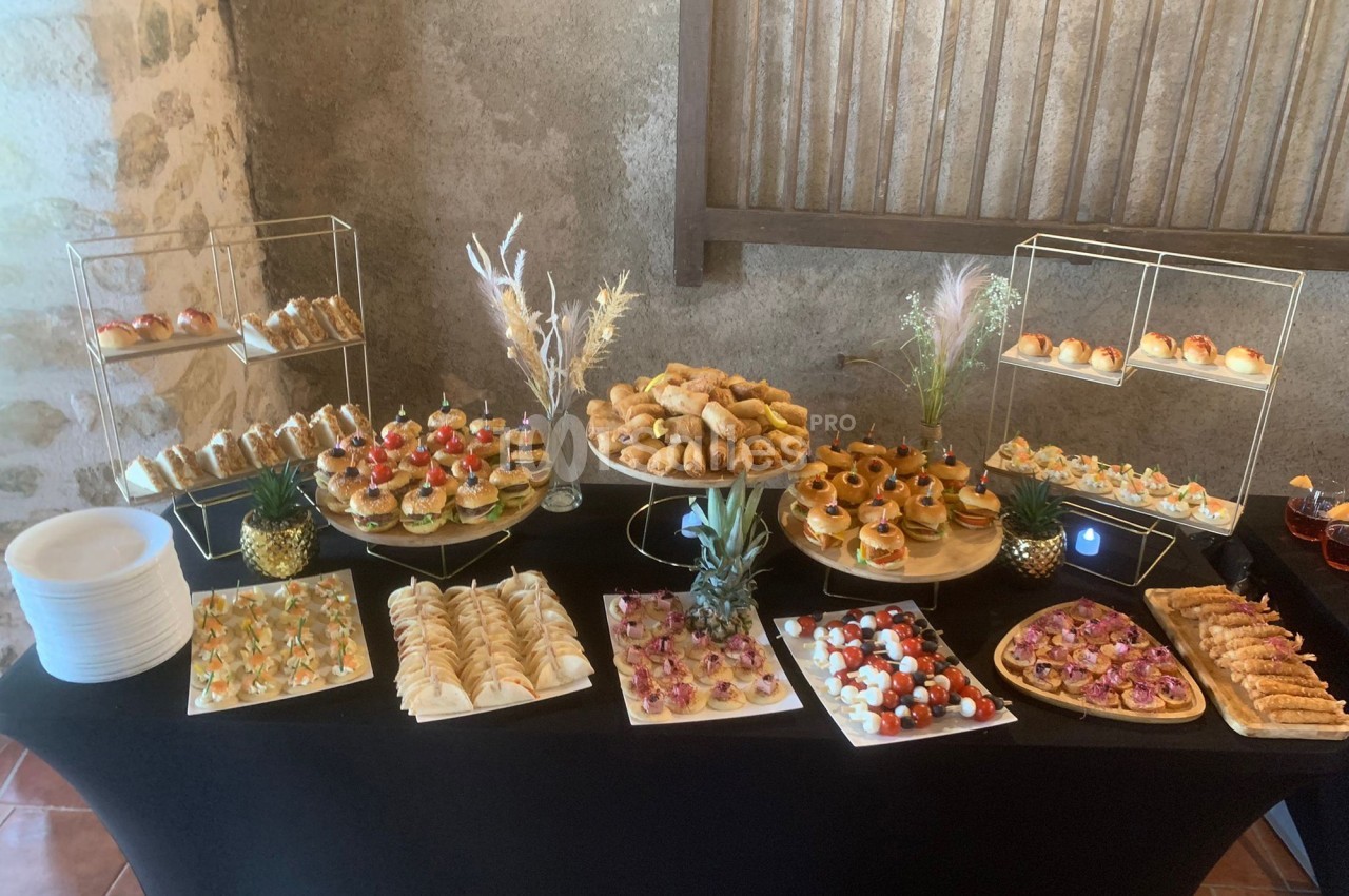 Buffet de pièces apéritives variées disposées sur une table noire, avec des présentoirs et décorations.
