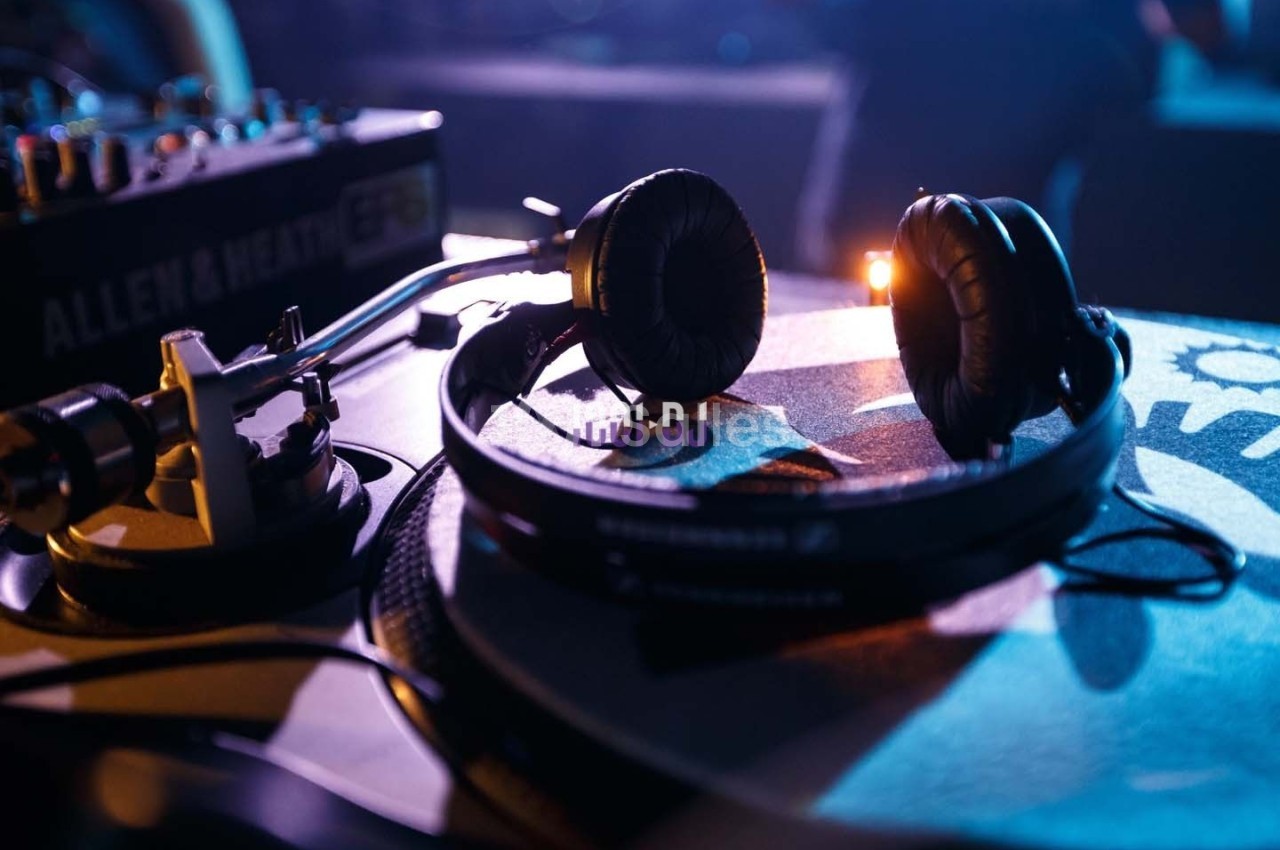 Casque audio posé sur une platine vinyle dans une ambiance lumineuse tamisée.