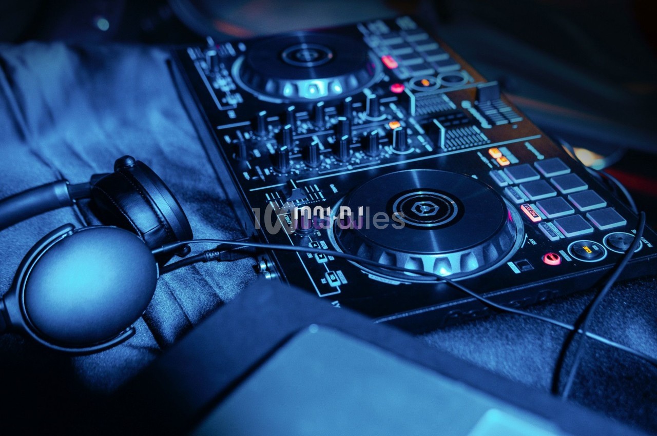 Table de mixage DJ avec casque audio posé à côté, éclairée par une lumière bleutée.