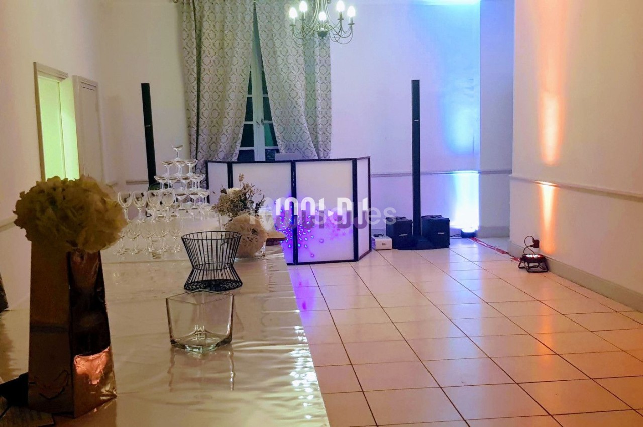 Salle de réception avec décoration lumineuse, table en verre, pyramide de coupes et équipement de sonorisation.