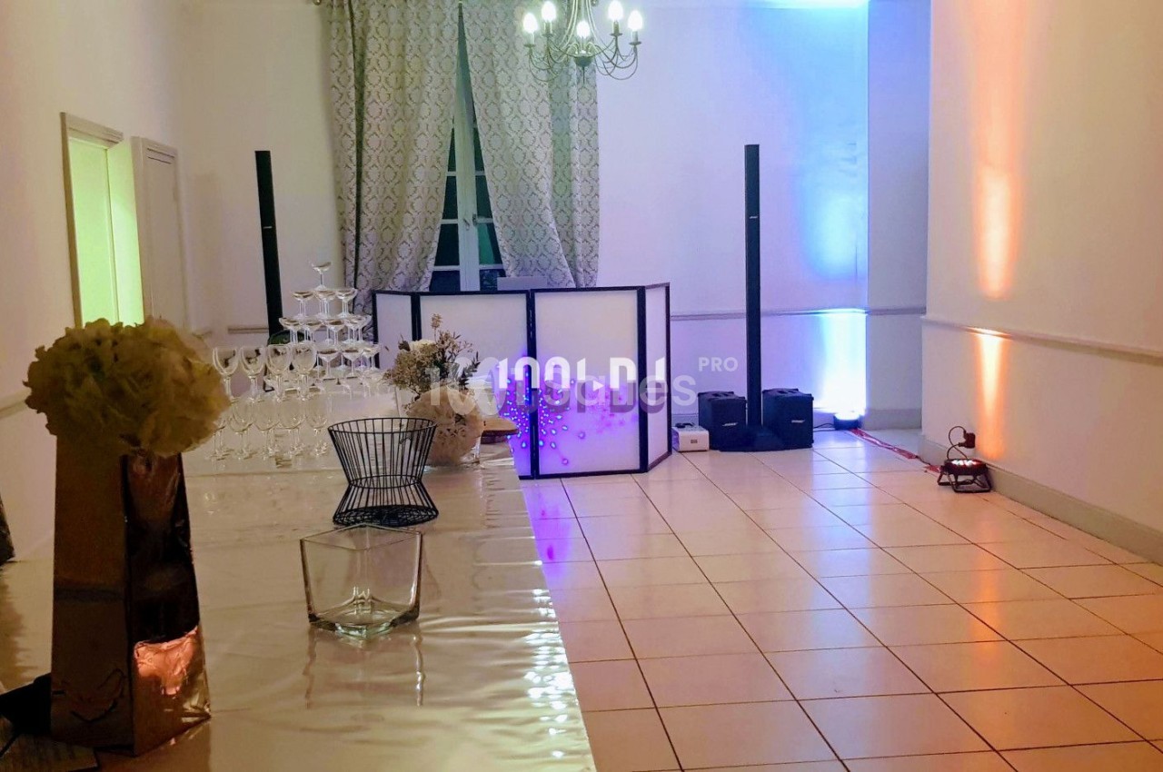 Salle de réception avec décoration lumineuse, table en verre, pyramide de coupes et équipement de sonorisation.