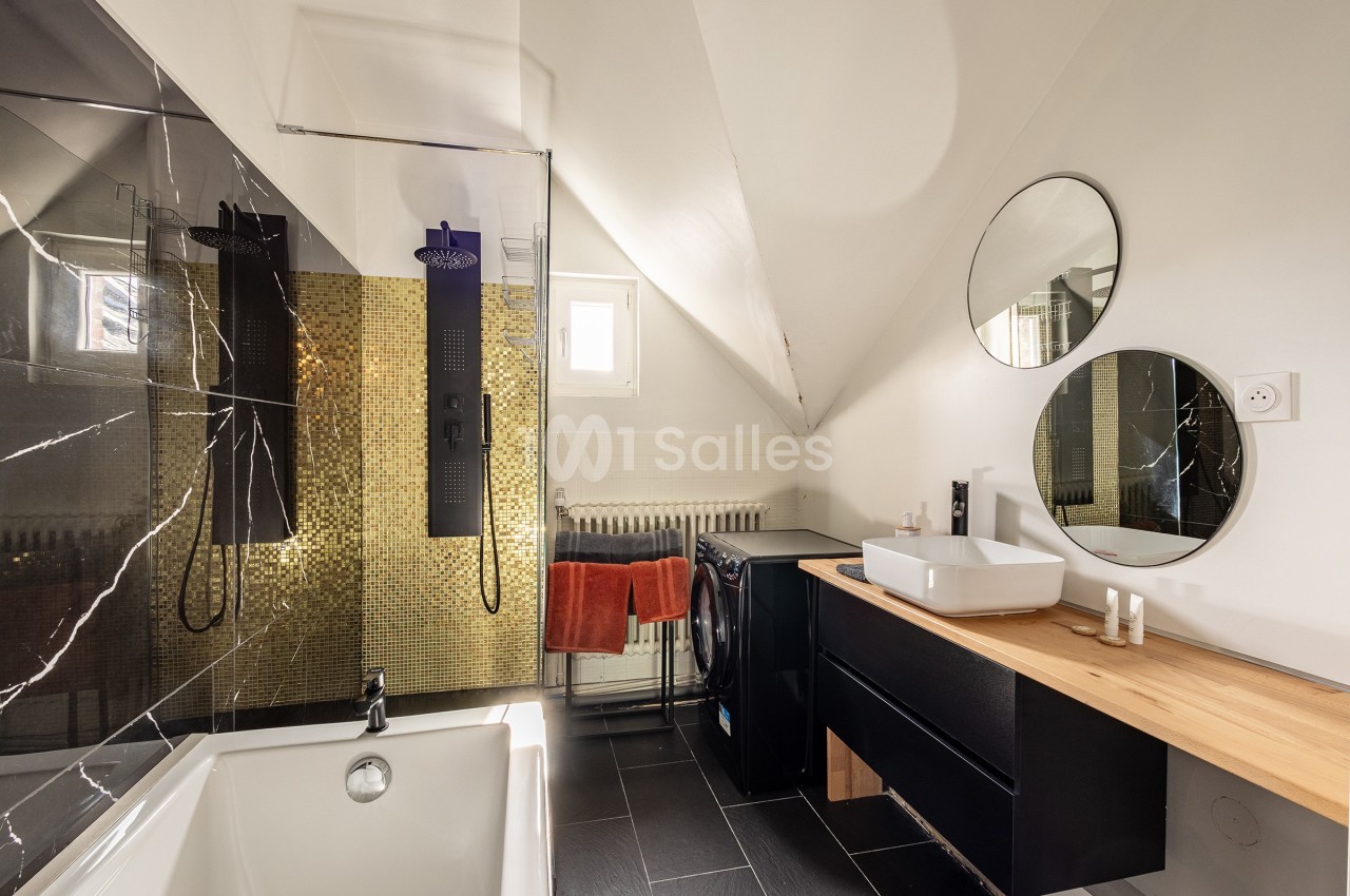 Salle de bain moderne avec baignoire, douche à l'italienne, vasque sur meuble en bois et murs partiellement carrelés.