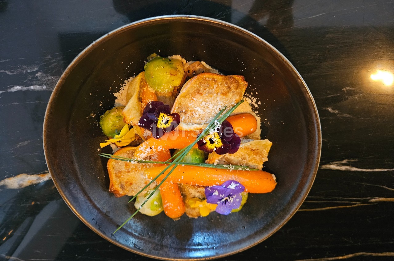 Assiette de légumes colorés avec carottes, choux de Bruxelles, fleurs comestibles et tranches de pain grillé.