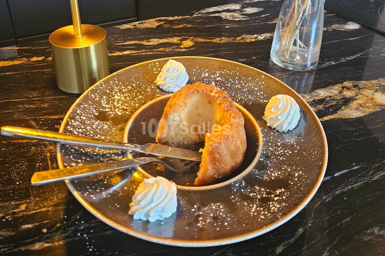 Dessert servi sur une assiette avec un gâteau moelleux, une cuillère, une fourchette et des rosettes de chantilly.