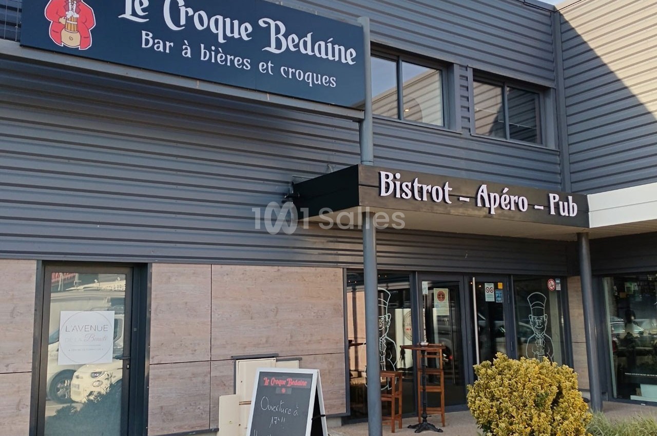 Façade d'un bistrot nommé ’Le Croque Bedaine’ avec terrasse, enseignes et ardoise présentant le menu.