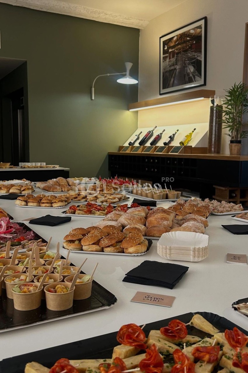 Buffet varié avec sandwichs, verrines, amuse-bouches et viennoiseries disposés sur une grande table blanche.