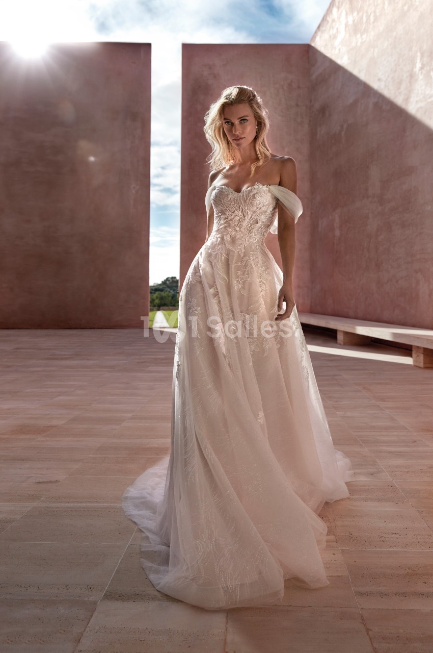 Femme portant une robe de mariée élégante dans un espace architectural minimaliste baigné de lumière naturelle.