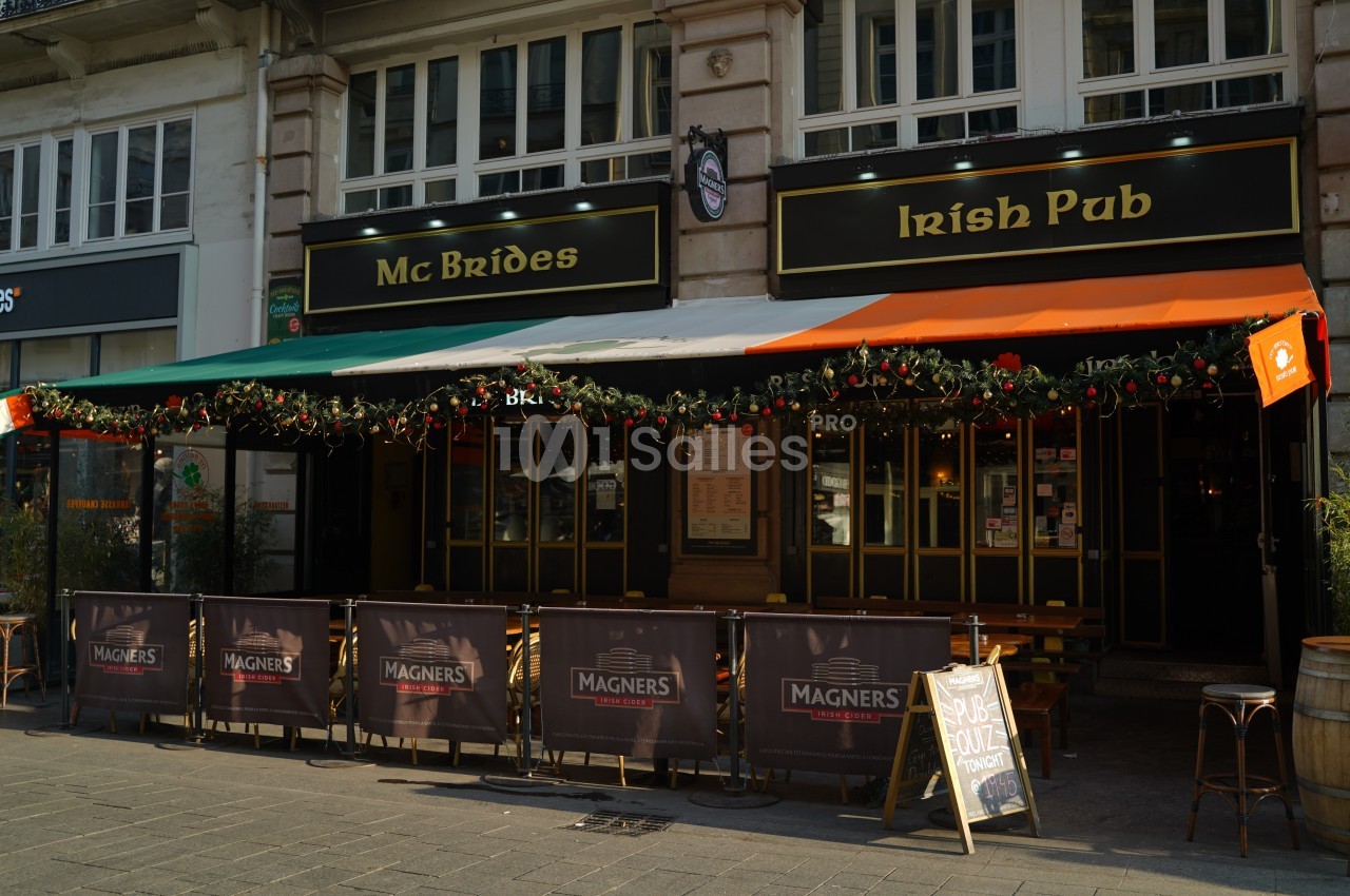 Façade d'un pub irlandais avec terrasse, décorations de Noël et enseignes visibles sous un auvent coloré.