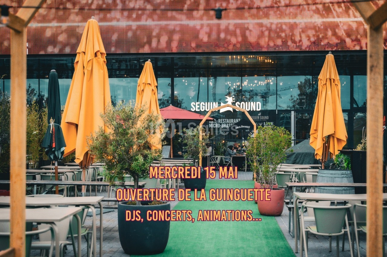 Terrasse avec parasols colorés devant un bâtiment, texte annonçant l'ouverture d'une guinguette avec animations.