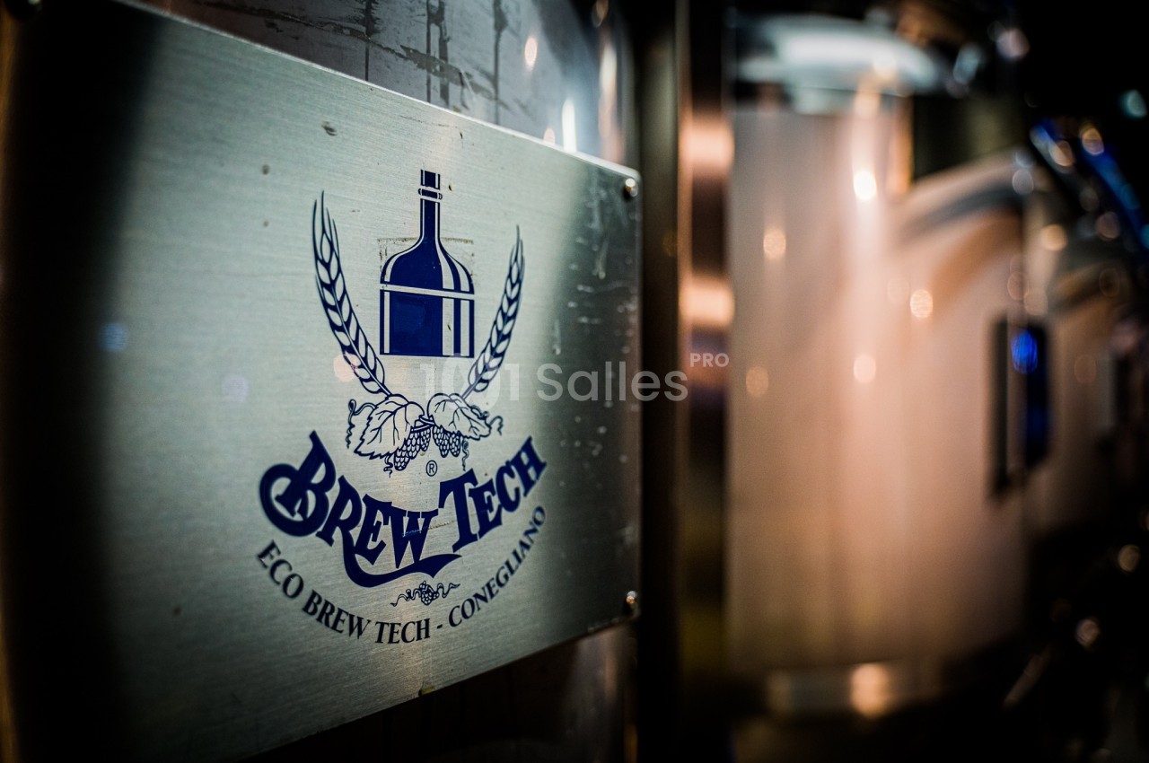Plaque métallique avec le logo ’Brew Tech’ sur un équipement industriel en acier inoxydable.