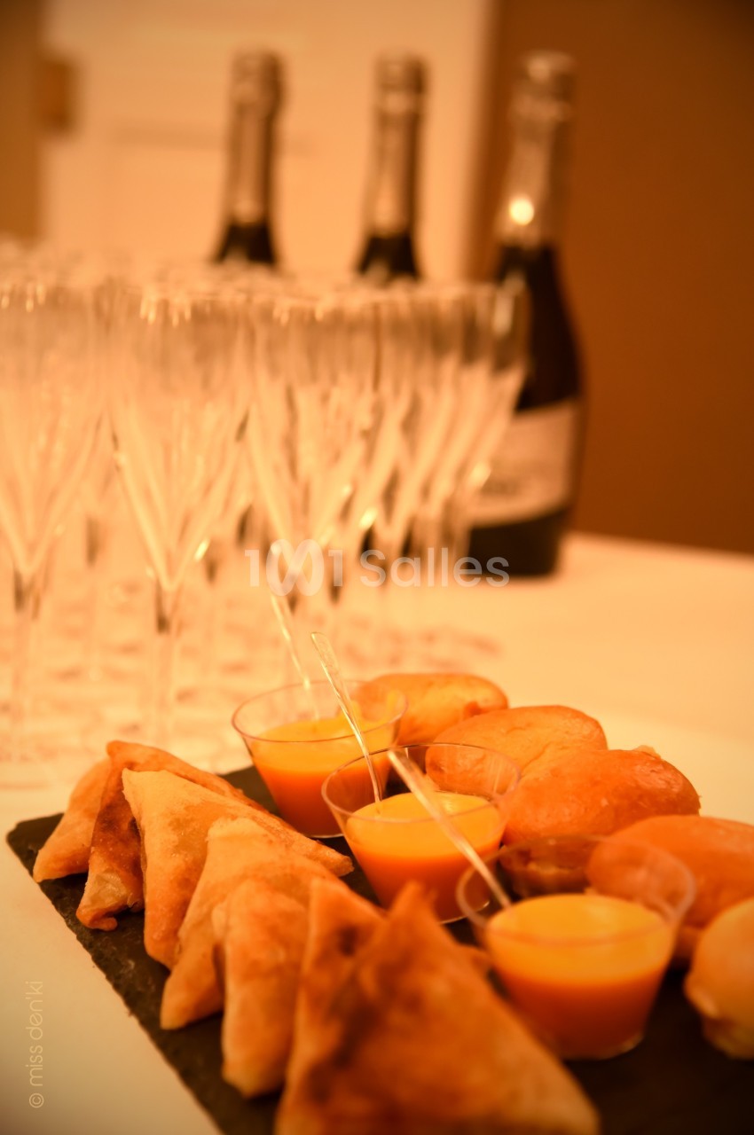 Plateau de bouchées salées avec verrines de soupe, samoussas et petits pains, accompagné de flûtes et bouteilles de…