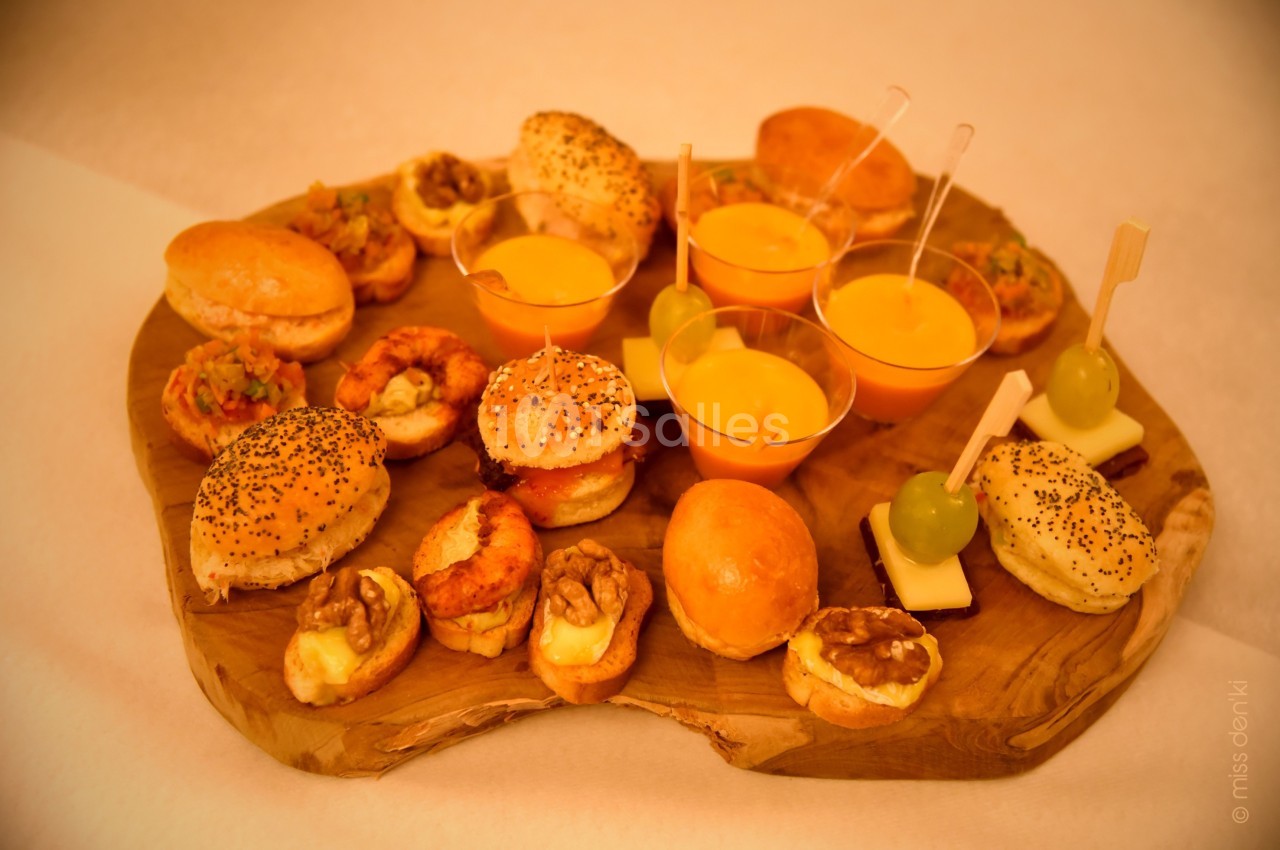 Plateau en bois garni de bouchées variées : mini-burgers, verrines, brochettes de fromage et fruits, noix et crevettes.