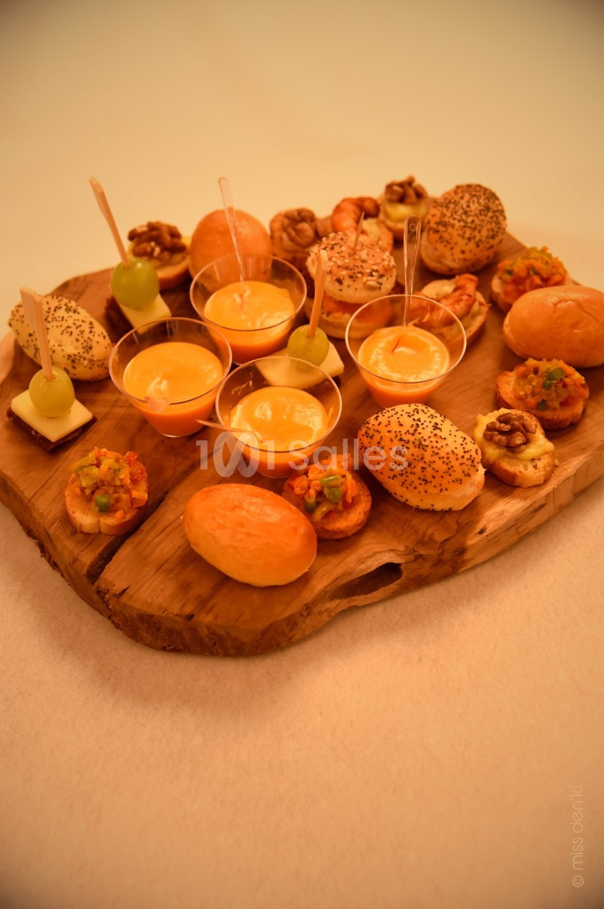 Plateau en bois garni de bouchées salées variées, mini-pains, verrines et amuse-bouches décorés.