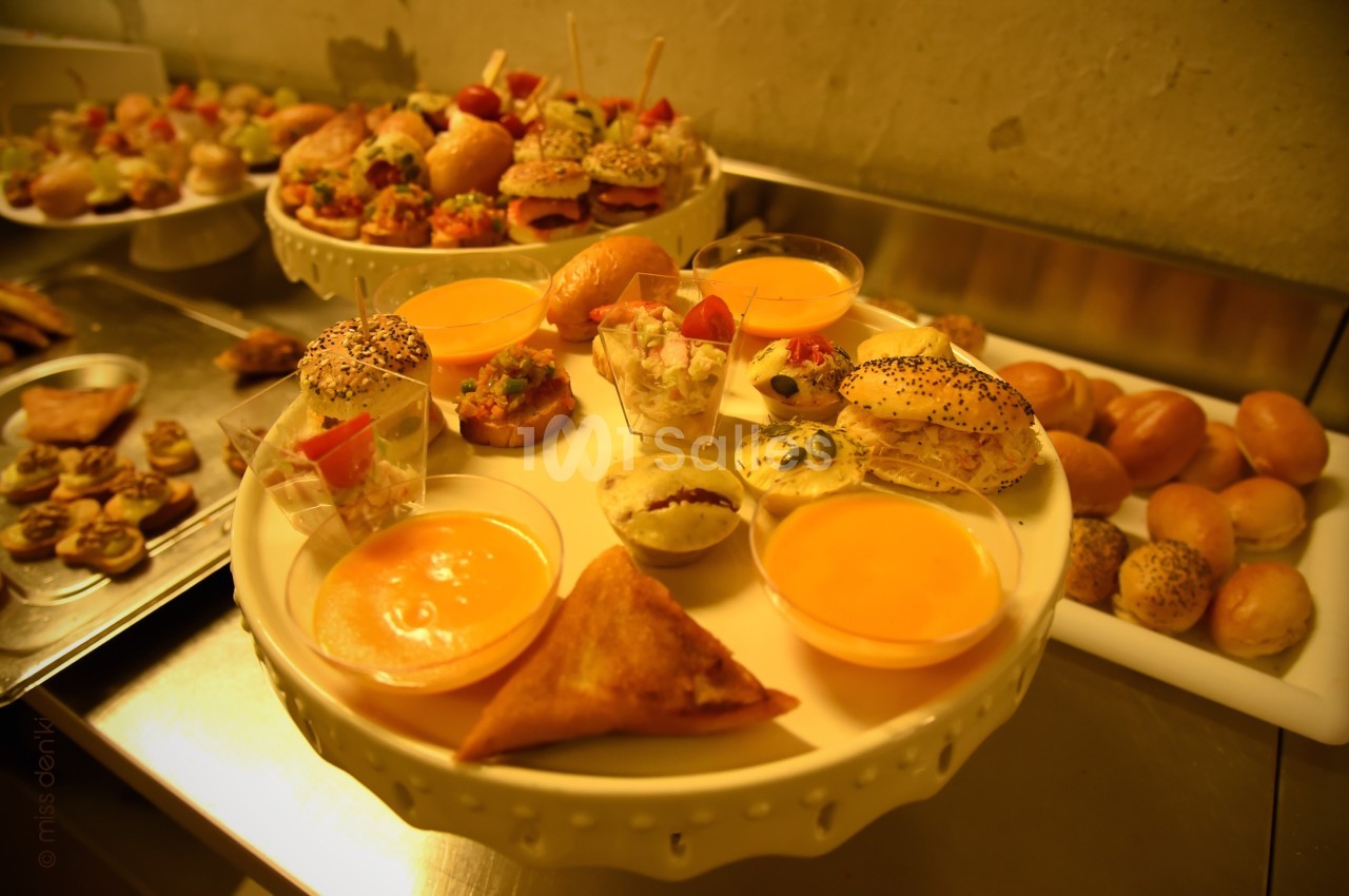 Plateau de bouchées salées variées et verrines disposé sur une table dans un cadre de restauration.