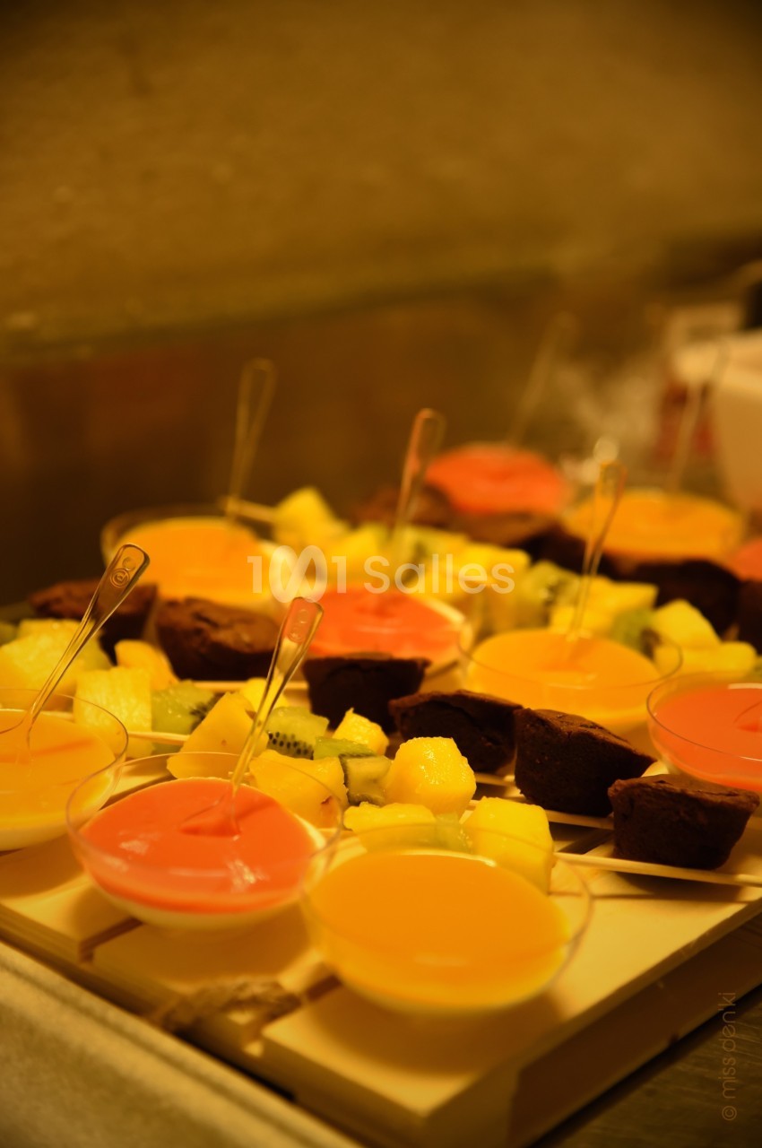 Assortiment de desserts colorés comprenant des verrines de fruits et des parts de gâteau disposés sur un plateau.