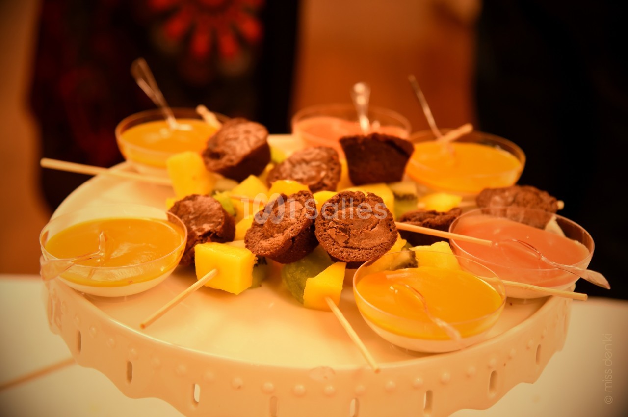 Assortiment de desserts sur un plateau, comprenant des verrines colorées, des morceaux de fruits et des mini-gâteaux.