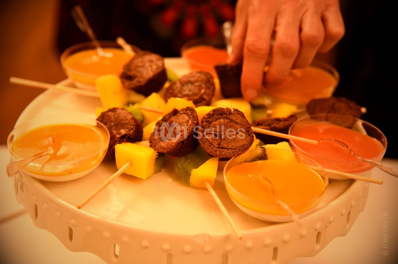Assortiment de desserts sur un plateau, incluant brochettes de fruits, sauces colorées et mini-gâteaux au chocolat.