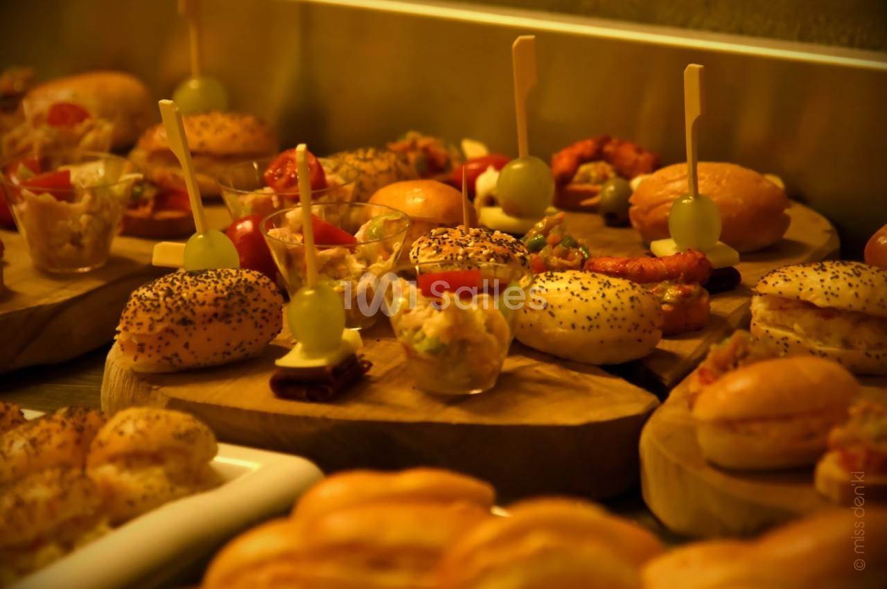 Plateau de mini-burgers, verrines et amuse-bouches variés disposés sur des planches en bois.