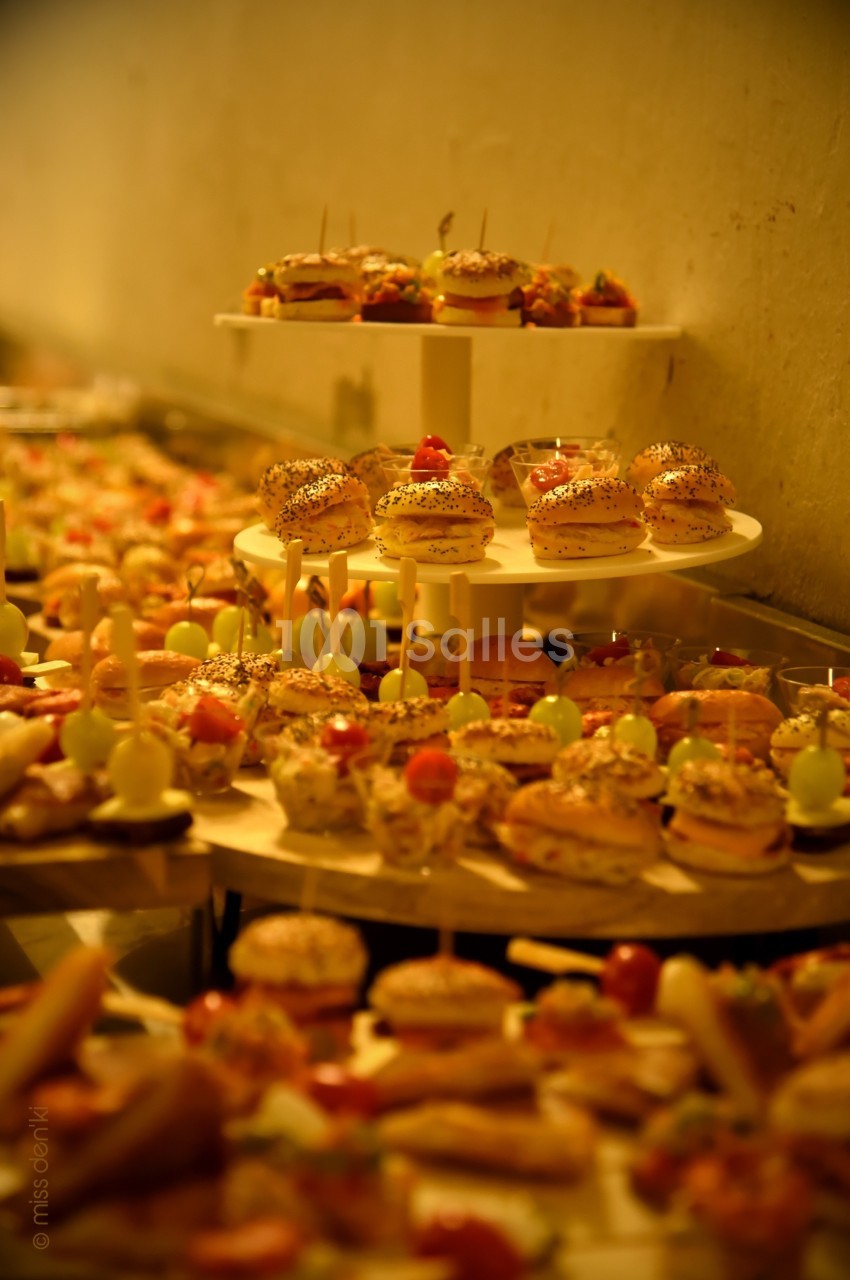 Plateaux de petits fours variés disposés sur plusieurs niveaux dans un cadre chaleureux et éclairé.