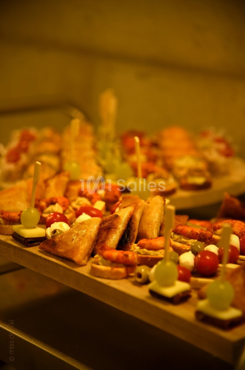 Plateaux garnis de divers amuse-bouches, incluant brochettes, feuilletés et bouchées apéritives, présentés sur une table.