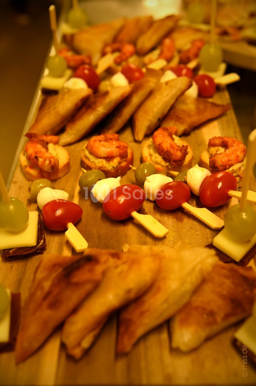 Plateau de bouchées apéritives variées comprenant samoussas, brochettes de légumes et crevettes sur toasts.