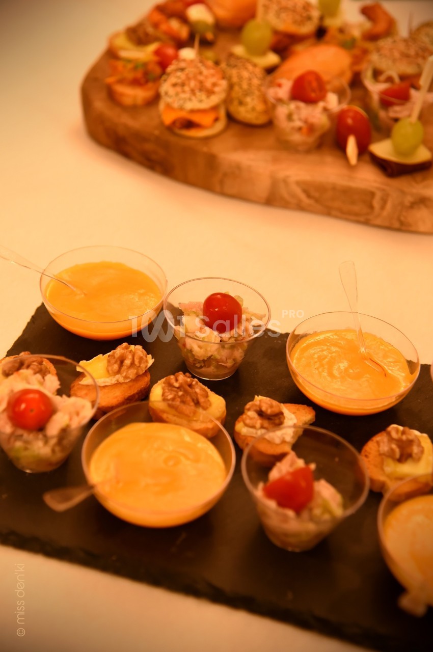 Assortiment de verrines et amuse-bouches variés disposés sur une ardoise et une planche en bois.