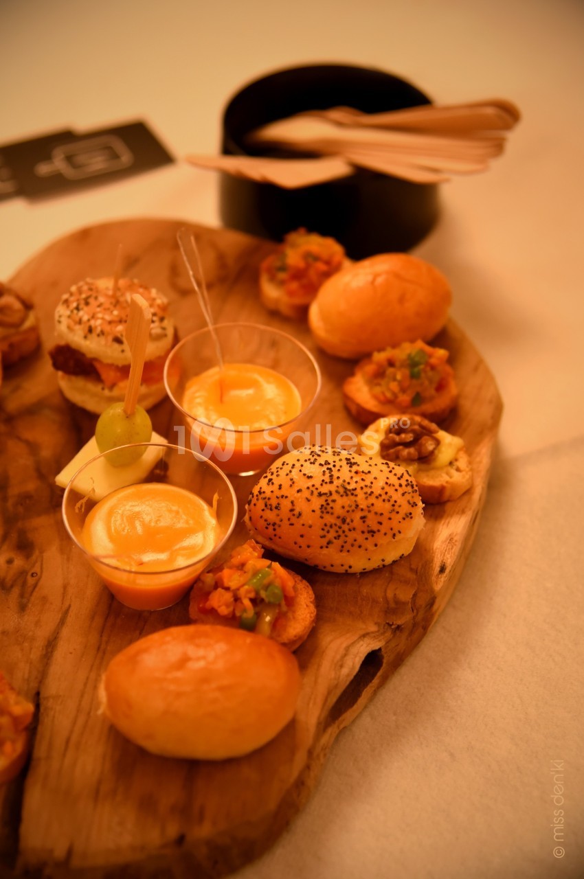 Plateau en bois avec assortiments de bouchées salées, verrines et pains garnis, accompagné de couverts en bois.