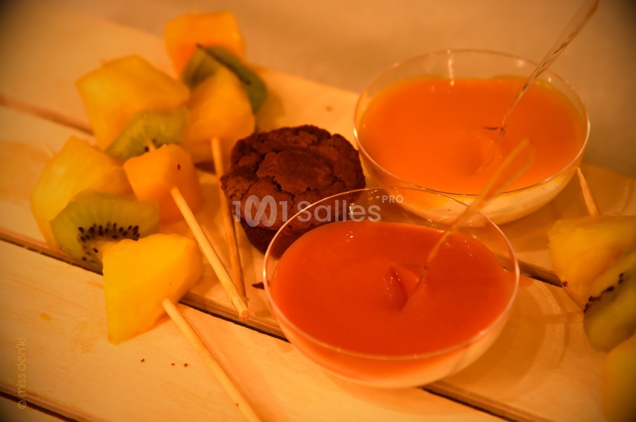 Brochettes de fruits frais avec kiwi et ananas, accompagnées de sauces et d'un petit gâteau au chocolat.
