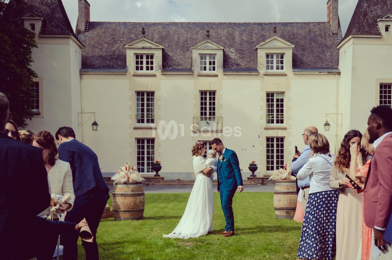 Un couple échange un baiser lors d'une cérémonie de mariage en plein air devant un bâtiment historique.