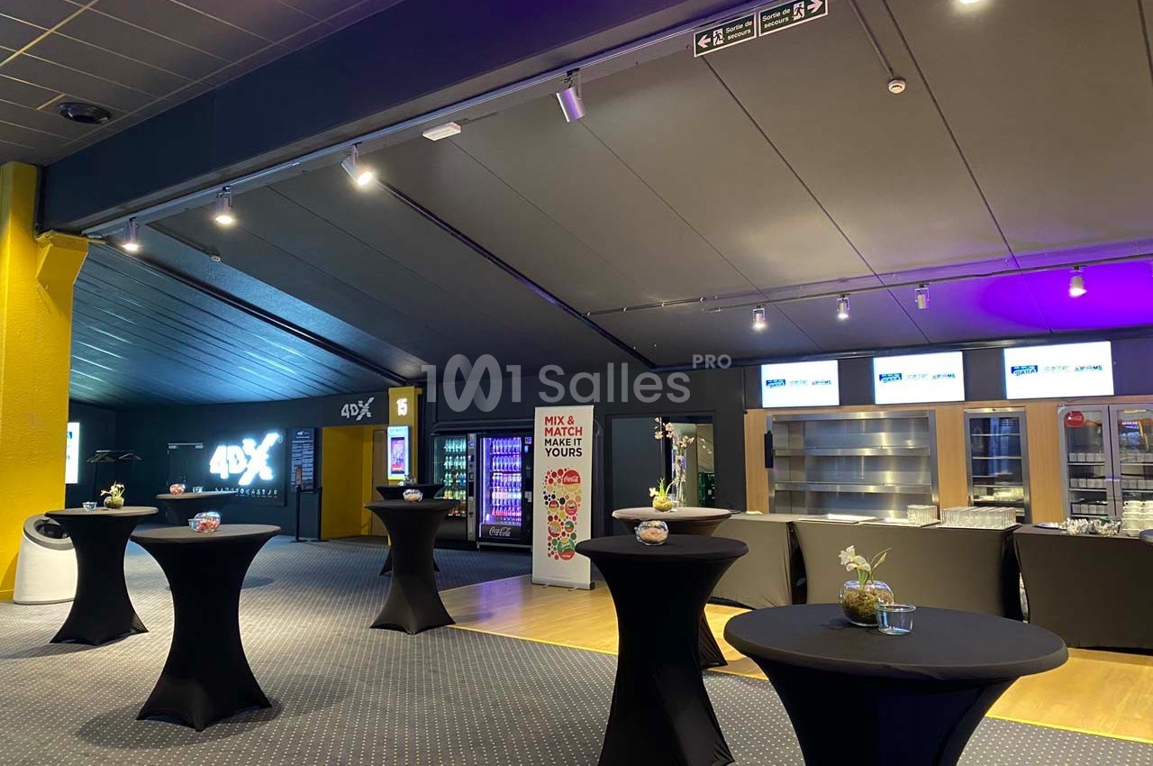 Espace intérieur avec tables hautes noires, distributeur automatique et éclairage tamisé dans un cadre moderne.