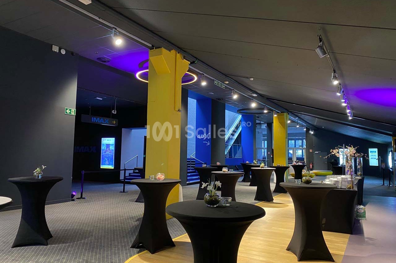 Salle moderne avec tables hautes noires, éclairage tamisé et décorations minimalistes, prête pour un événement.