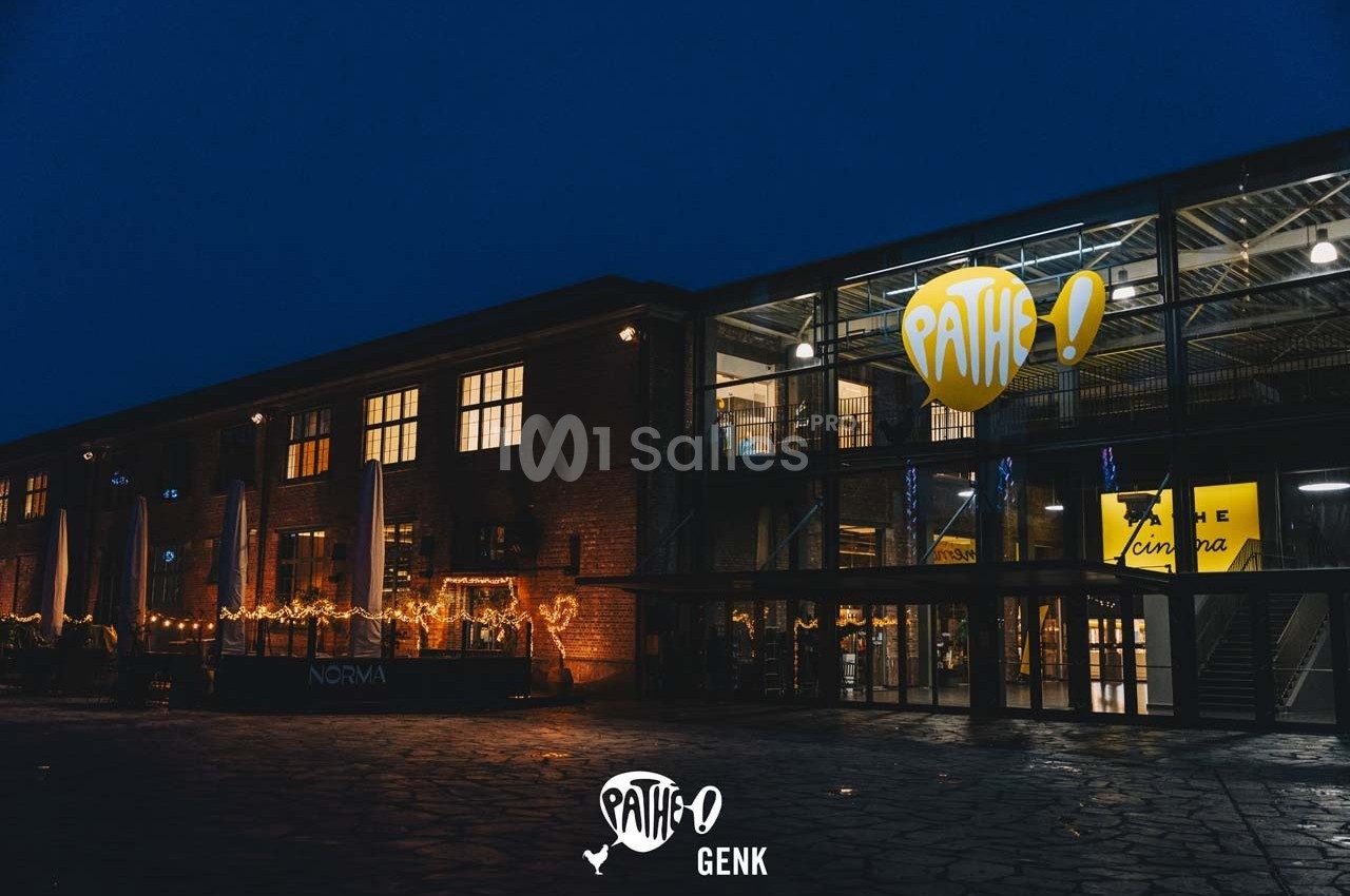Façade éclairée d'un cinéma Pathé en soirée, avec des décorations lumineuses et des baies vitrées visibles.