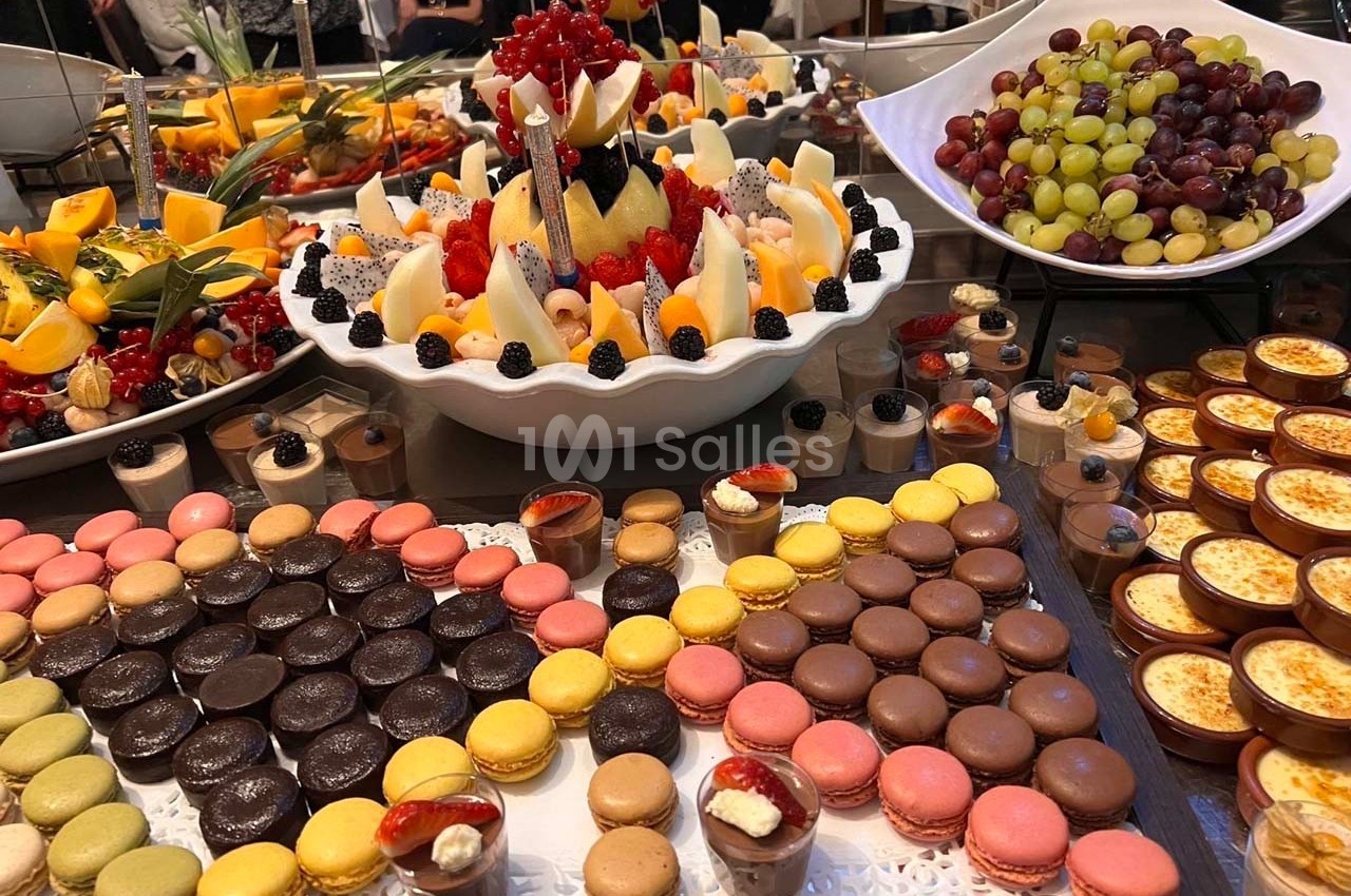 Buffet de desserts variés avec macarons colorés, fruits frais, verrines et tartelettes disposés sur une table.