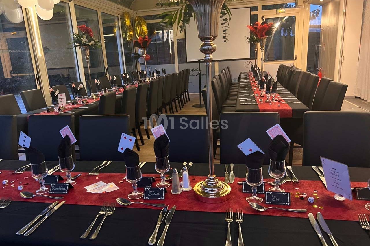 Salle de réception décorée avec des tables dressées sur le thème du casino, ornées de cartes et de jetons.