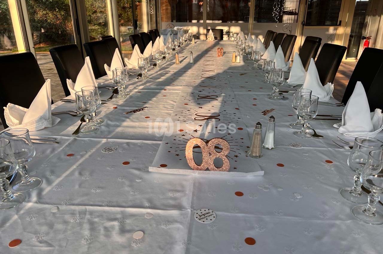 Table dressée pour un événement, décorée de confettis et serviettes pliées, avec des chaises alignées autour.