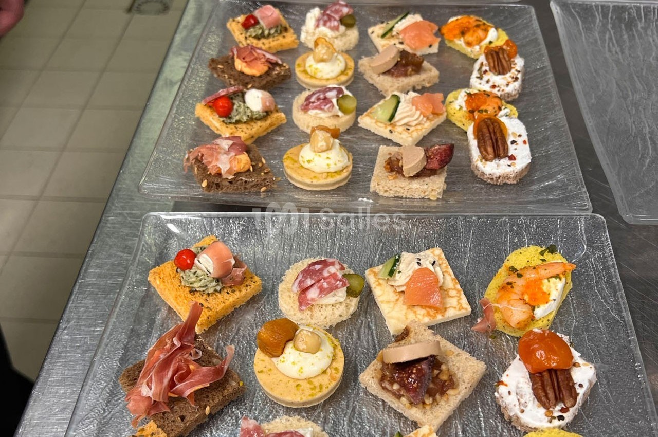 Plateaux de canapés variés avec des garnitures colorées, disposés sur une table en cuisine.