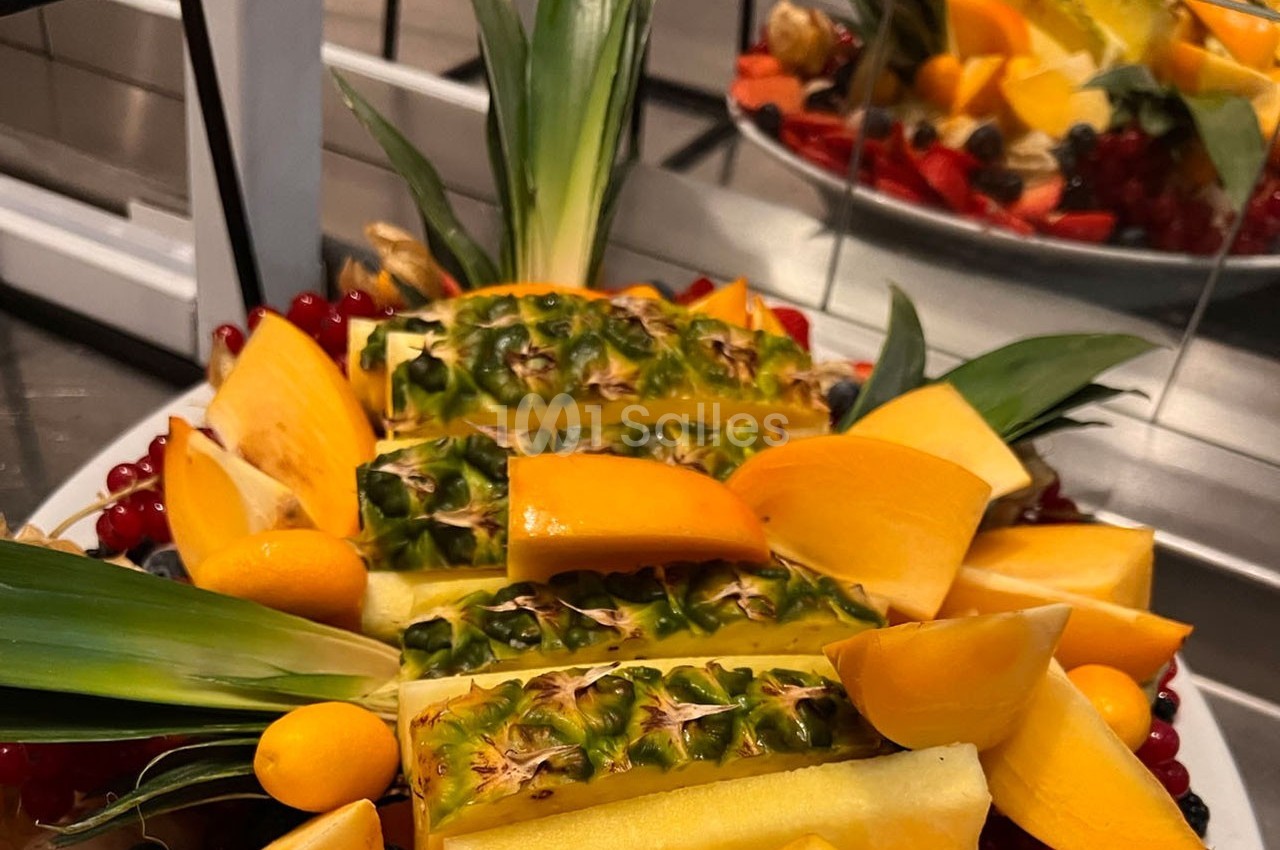 Assortiment de fruits frais comprenant ananas, kakis, groseilles et autres fruits colorés disposés sur un plateau.