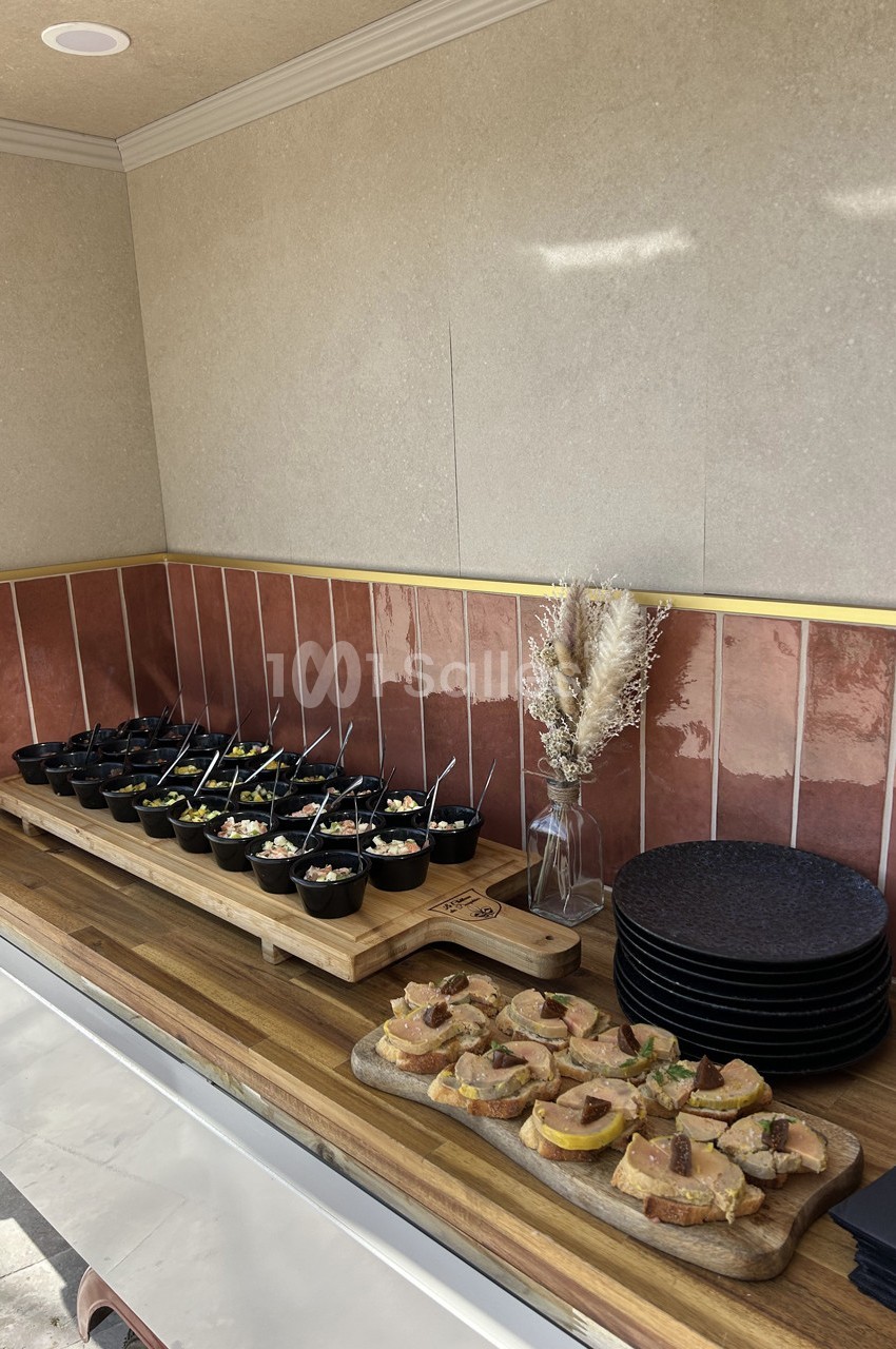 Buffet avec verrines et toasts disposés sur des planches en bois, près d'assiettes empilées et d'une décoration florale.