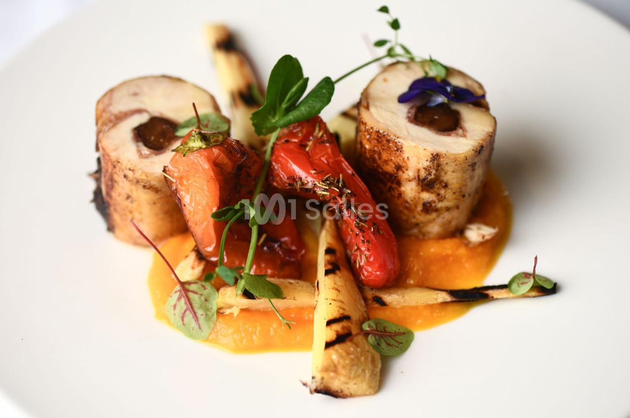 Assiette gastronomique avec roulés de volaille, légumes grillés, purée orange et herbes fraîches.